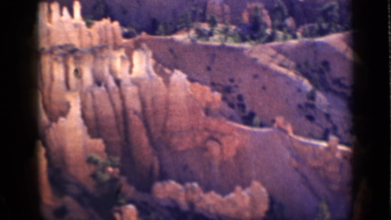 1939 Utah home-movie frame showing orange eroded rock formations and scattered vegetation in warm light.