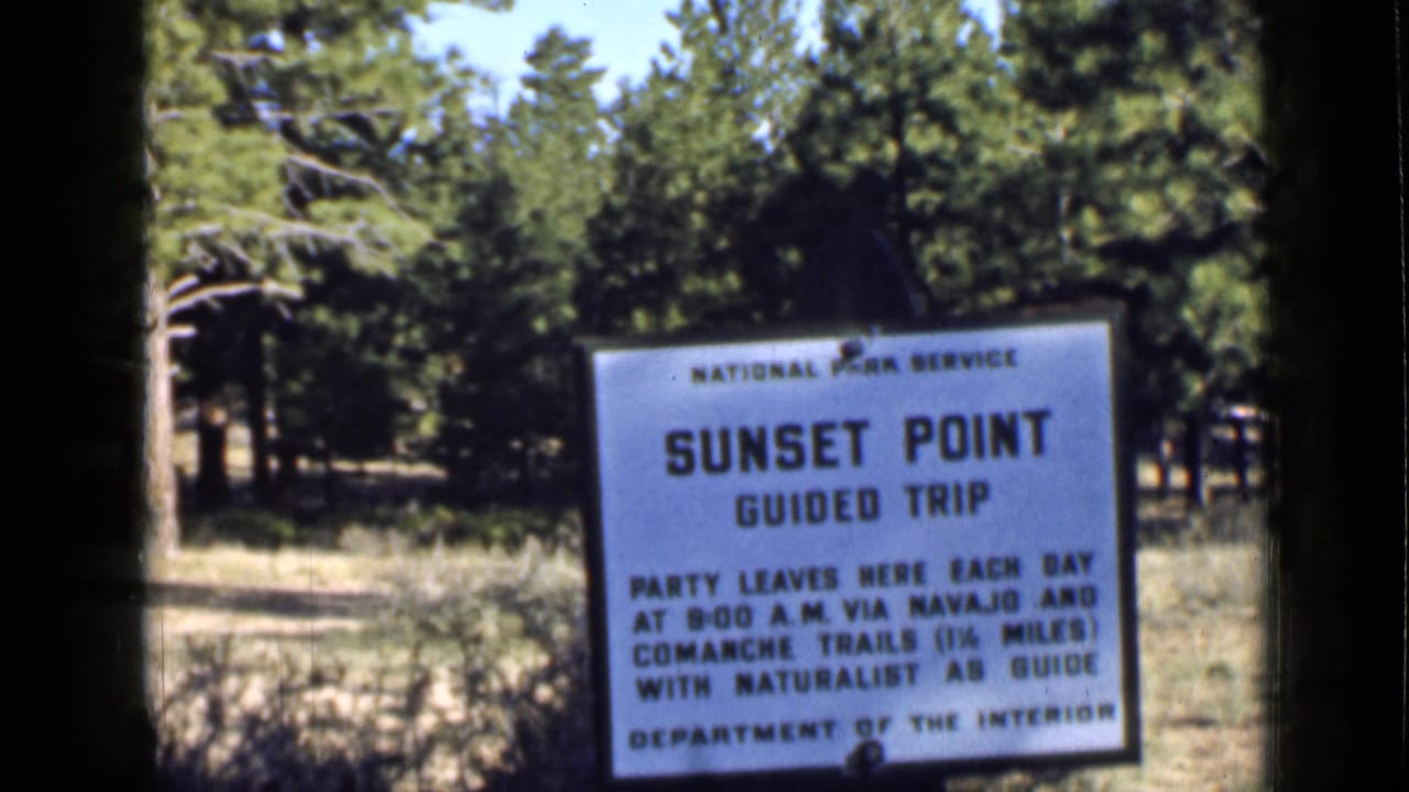 A National Park Service sign for Sunset Point Guided Trip stands among trees in the Utah park setting.
