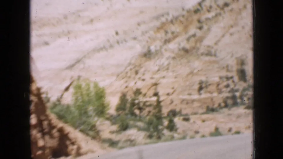 The 1939 Utah frame holds on the pale desert hillside, roadside vegetation, and road near the Zion entrance area.