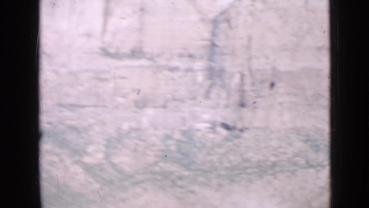 Utah 1939 home-movie frame looking past a dark window frame toward a pale rocky cliff under bright sky.