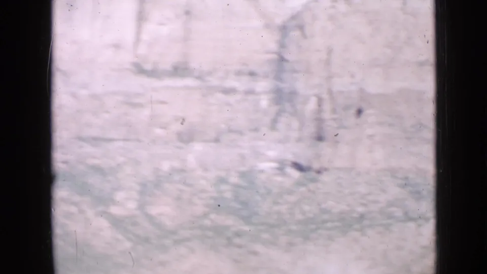 Utah 1939 home-movie frame looking past a dark window frame toward a pale rocky cliff under bright sky.