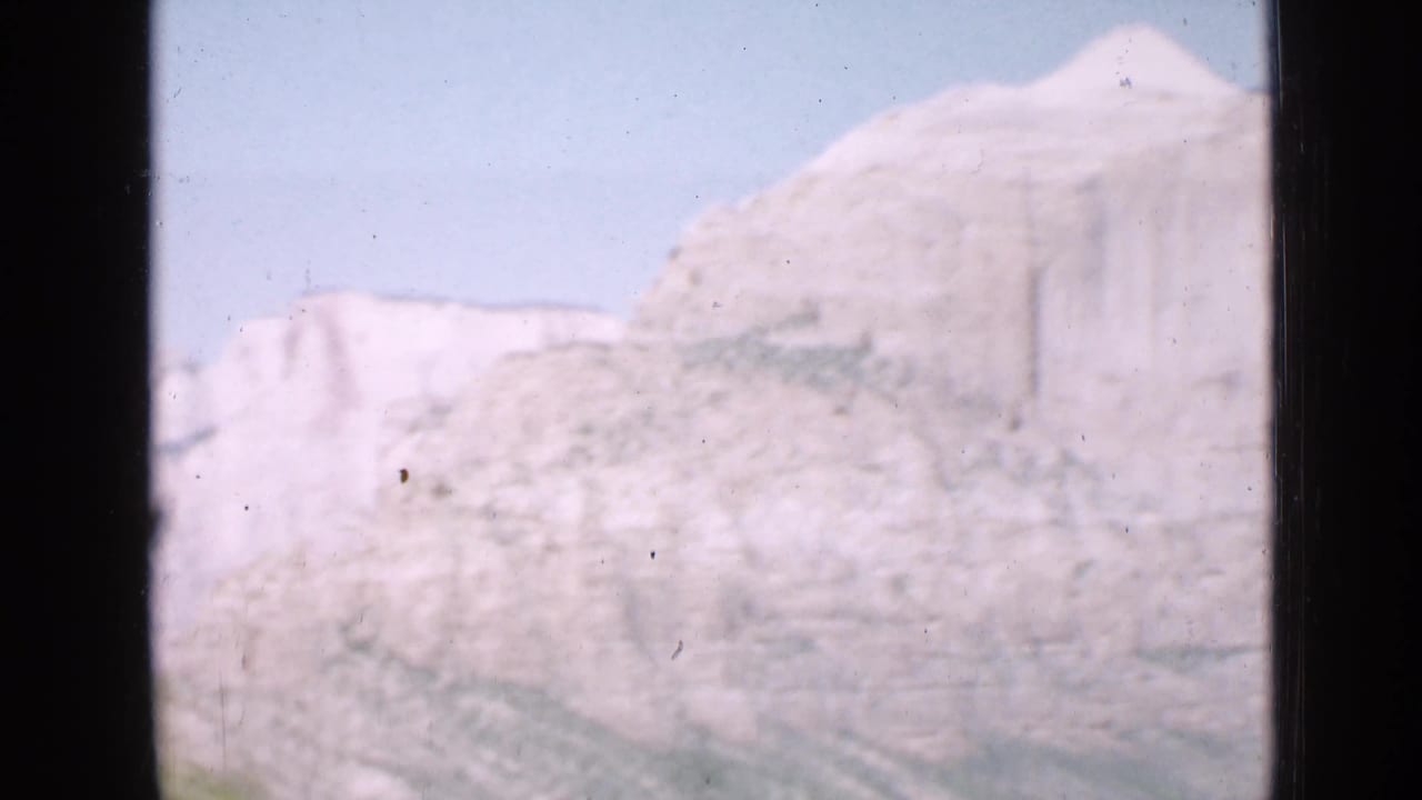 Soft 8mm view of a pale Utah cliff and blue sky, partially obscured by dark vertical framing.