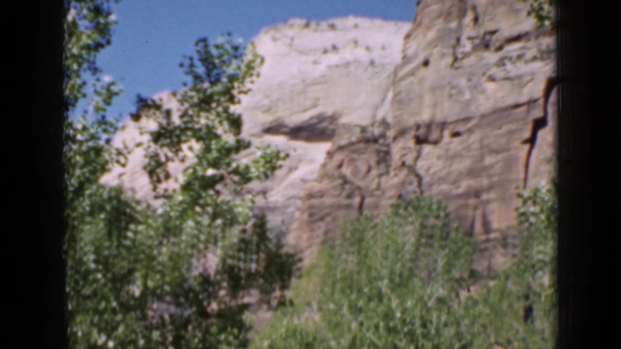 Utah rock formations and leafy trees appear under a clear sky in a 1939 8mm home-movie frame.