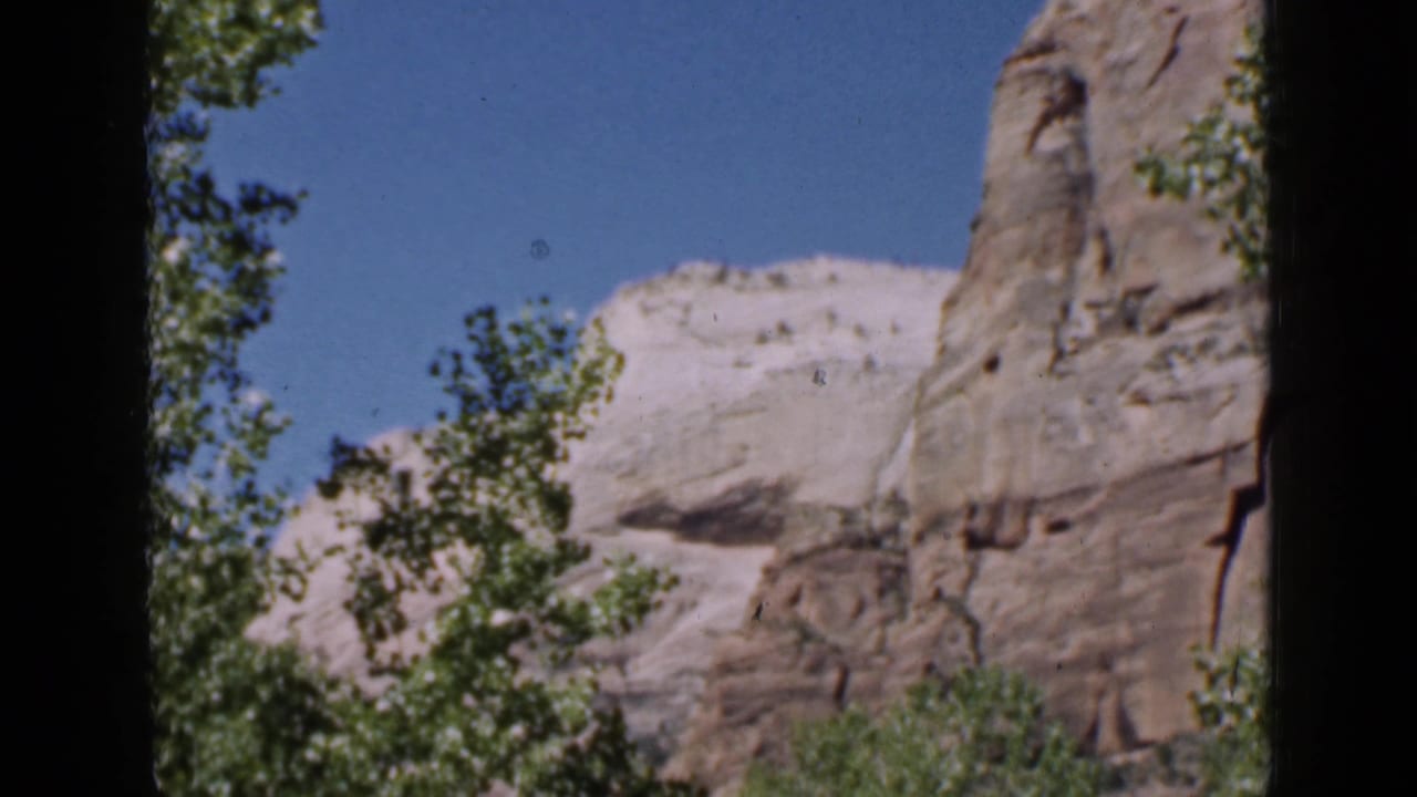 Rock formations and trees framed by dark vertical film borders.
