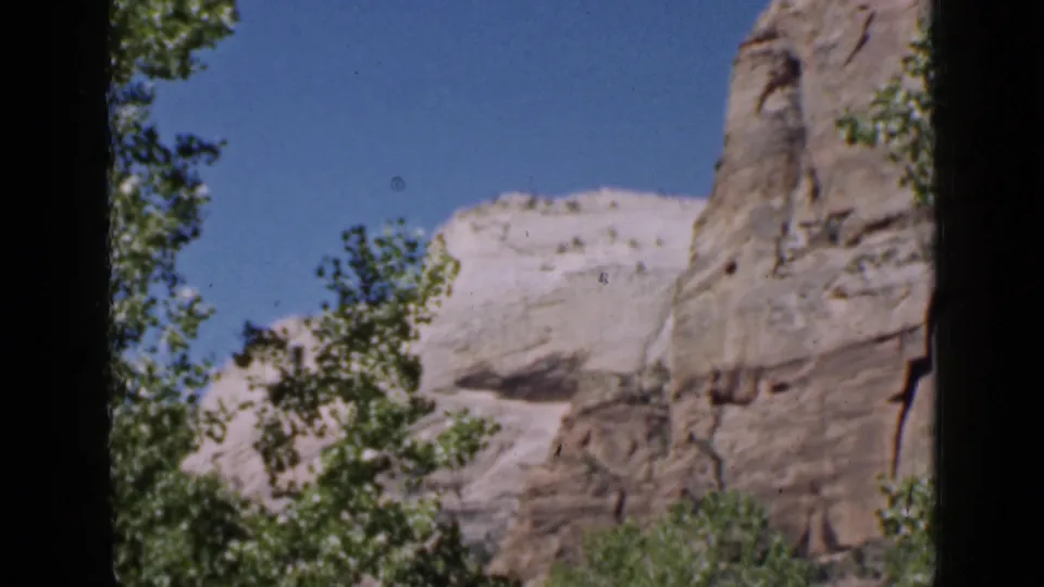 A second view of Utah canyon-like rock formations and trees, framed by the dark edges of the 8mm scan.