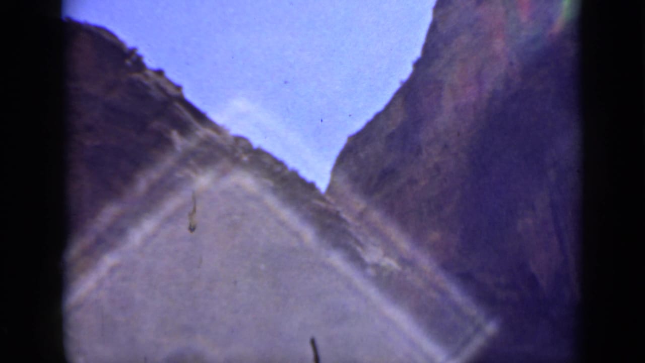 A final handheld canyon view in the Utah home movie frames rock walls against blue sky, with visible film edges and sun flare.
