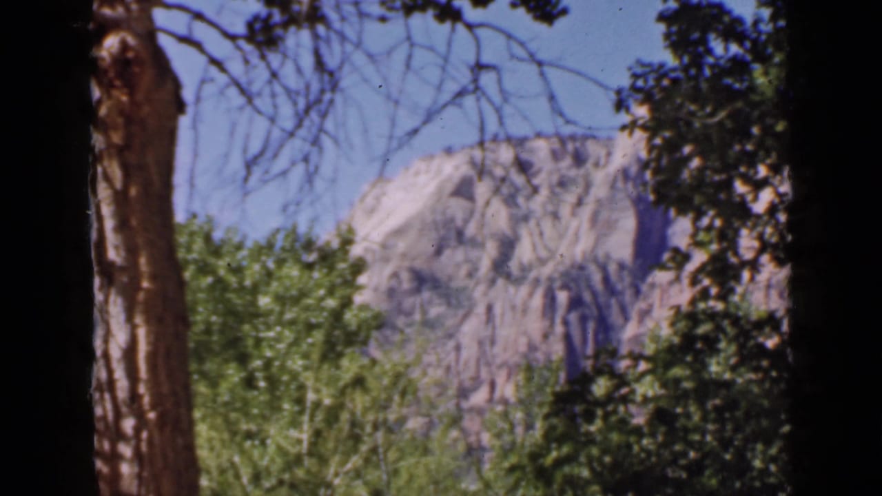 Utah canyon scenery from a 1939 8mm home movie, with bright rock formations visible through shaded trees.
