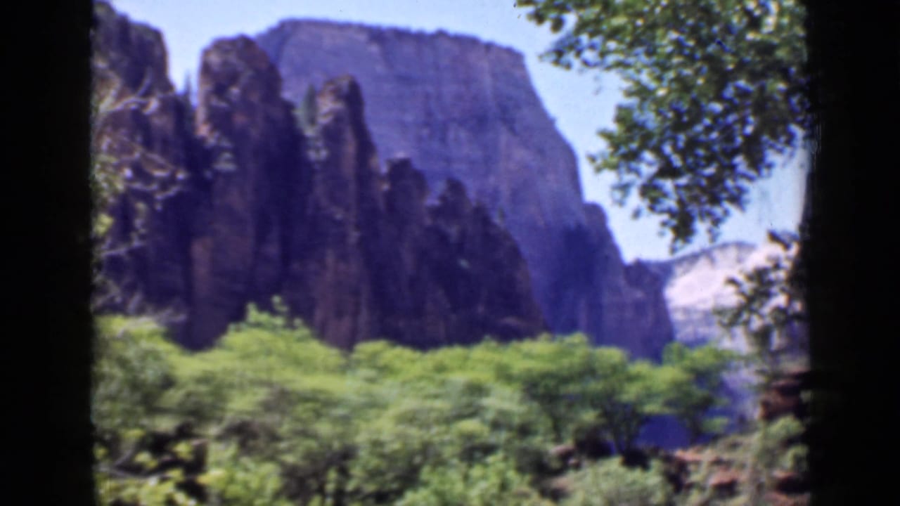 Late-1930s 8mm view of a Utah canyon landscape, with dark rock formations framed by trees.