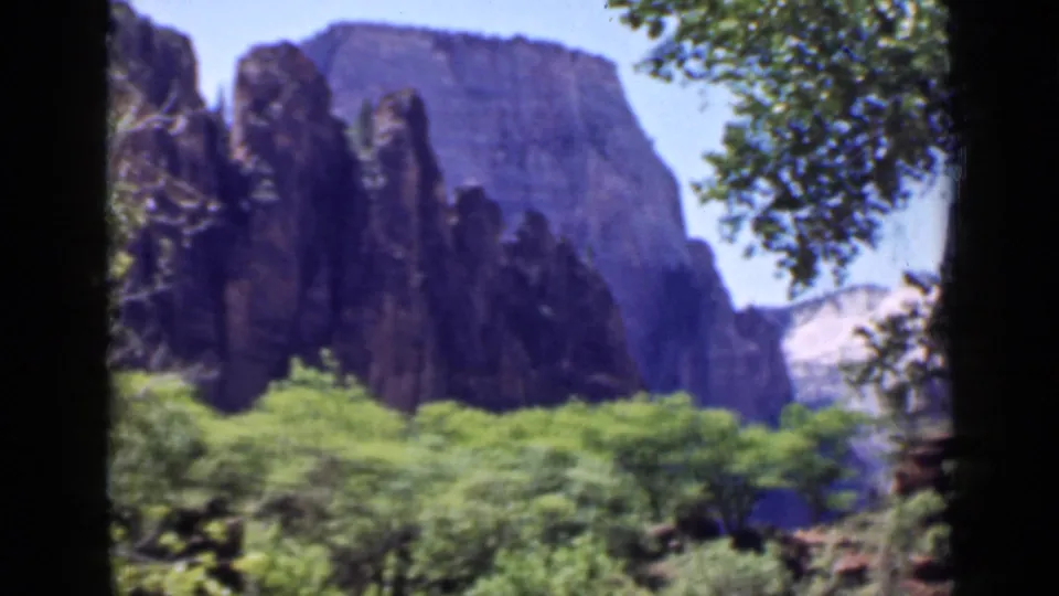 Late-1930s 8mm view of a Utah canyon landscape, with dark rock formations framed by trees.