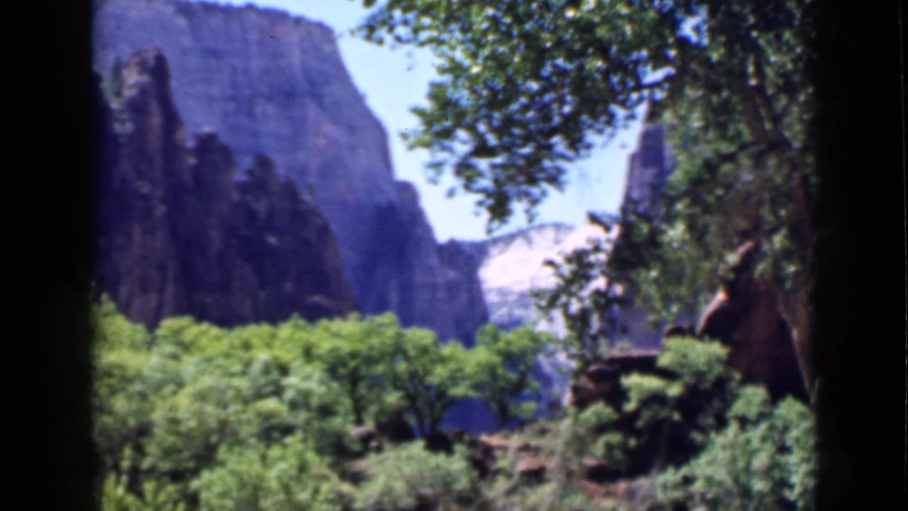 1939 Utah home-movie view of distant sandstone walls framed by trees, with soft focus and saturated color.