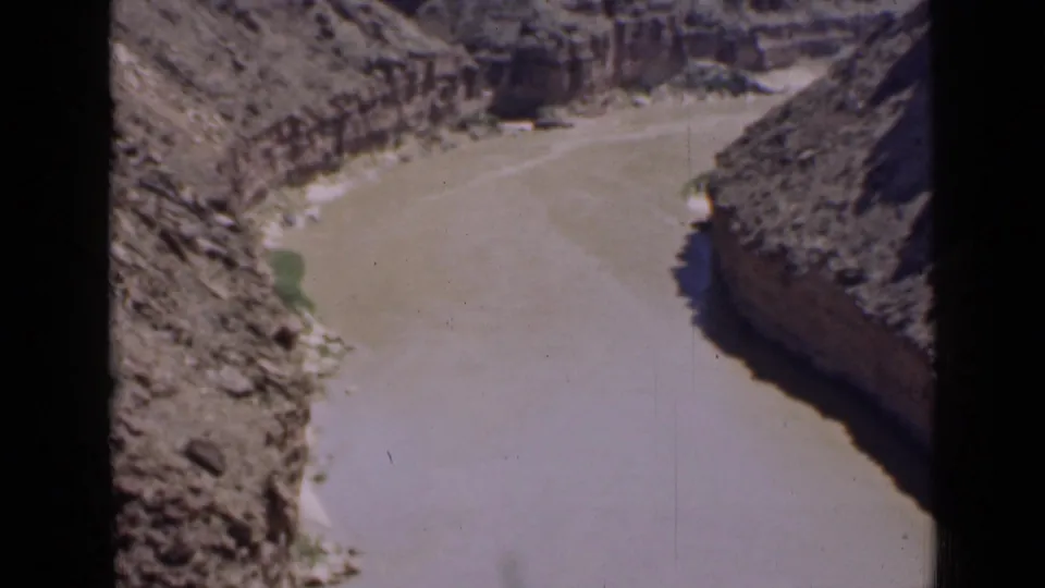 1939 Utah 8mm frame showing the broad muddy river channel below rough canyon walls and arid slopes.