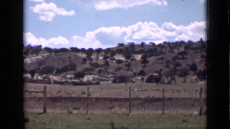 Rural Utah scenery in a 1939 8mm frame, with a fence across the foreground and soft hills beneath scattered clouds.