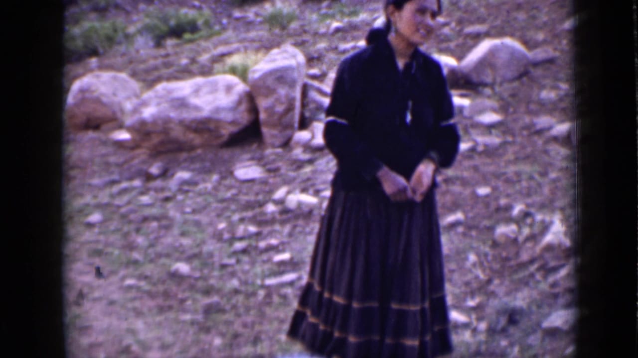 Young woman in dark traditional-looking dress stands on a rocky Utah hillside in 1939 home-movie footage.