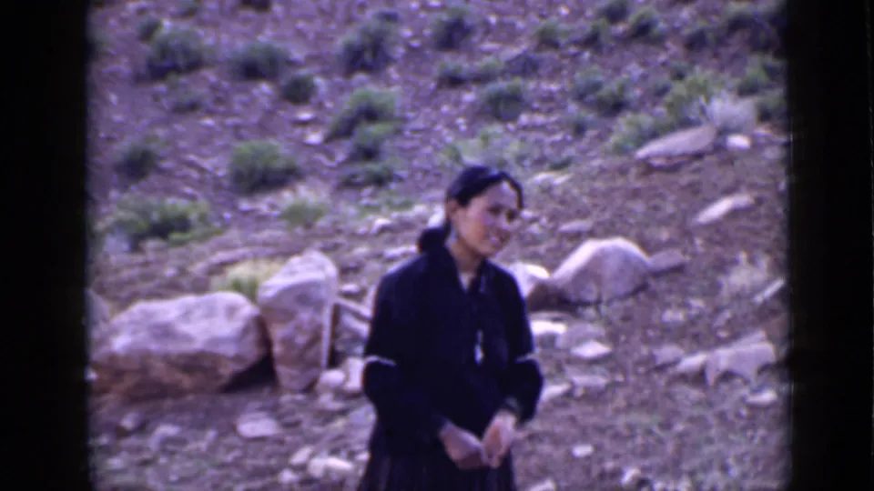 Young woman in dark clothing stands in profile-leaning pose against a rocky Utah hillside, with visible 8mm color shift.