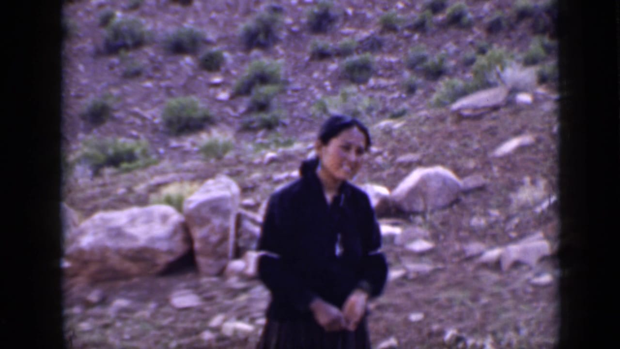 A woman in dark clothing appears to smile slightly while standing on a rocky Utah slope in 1939 home-movie footage.