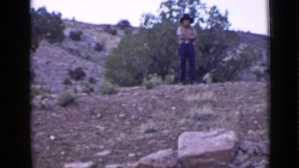 The 1939 Utah home movie shows a man in a cowboy hat standing on a rocky hillside with sparse vegetation behind him.