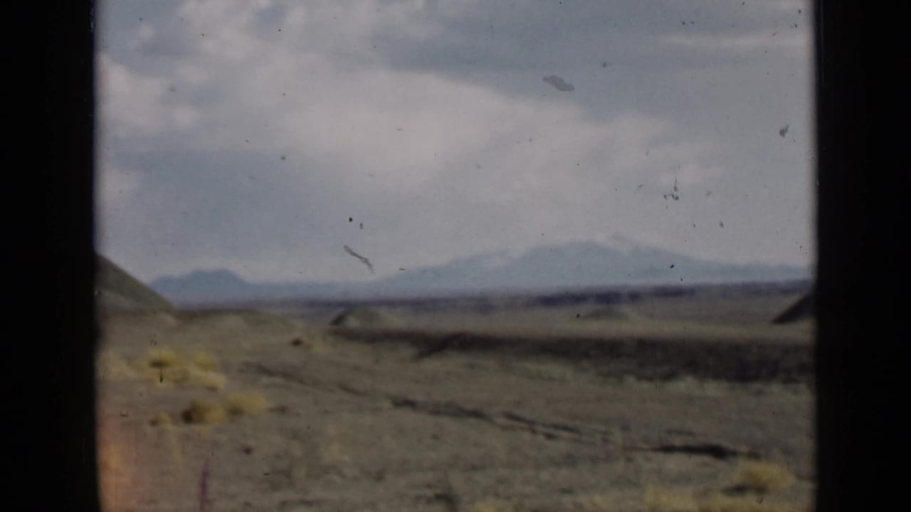 1939 Utah home-movie frame showing open arid ground, low hills, distant mountains on the horizon, and dark 8mm frame edges.