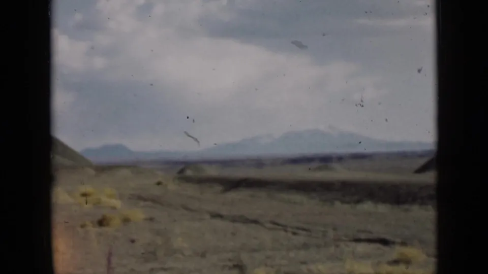 1939 Utah home-movie frame showing open arid ground, low hills, distant mountains on the horizon, and dark 8mm frame edges.