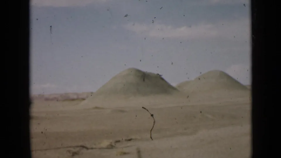 1939 Utah 8mm frame with two rounded desert hills, a flat sandy plain, pale sky, and visible dust and scratches from the film scan.
