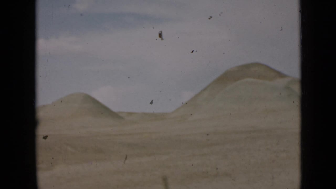 Distant rounded desert hills with open sandy ground in front.
