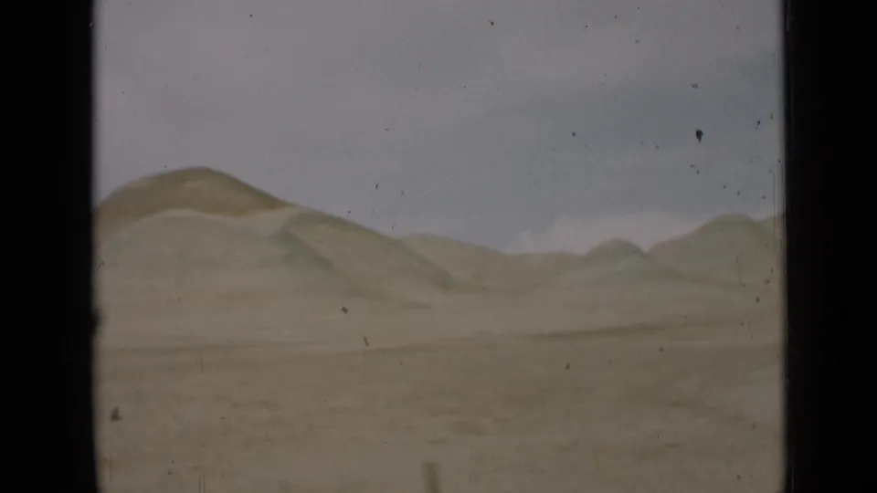 1939 Utah home-movie frame with rolling desert hills along the horizon, sparse open foreground, pale sky, and dark 8mm frame borders.