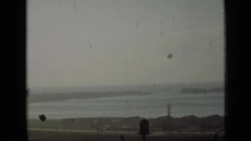 1940 Ontario home-movie frame showing a hazy waterside corridor, low shore, and tower from a fixed viewpoint.