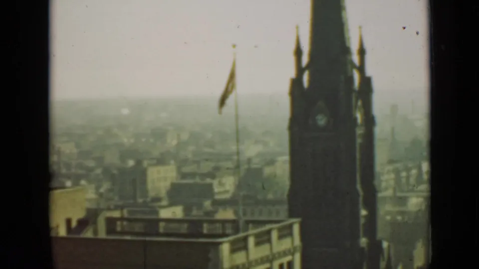 1940 Ontario city view with a prominent dark clock tower, small flag, flat roofline, and softened distant buildings.