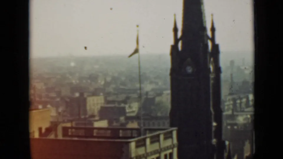 1940 Ontario 8mm frame with the clock tower partly silhouetted against a muted skyline and flagpole.
