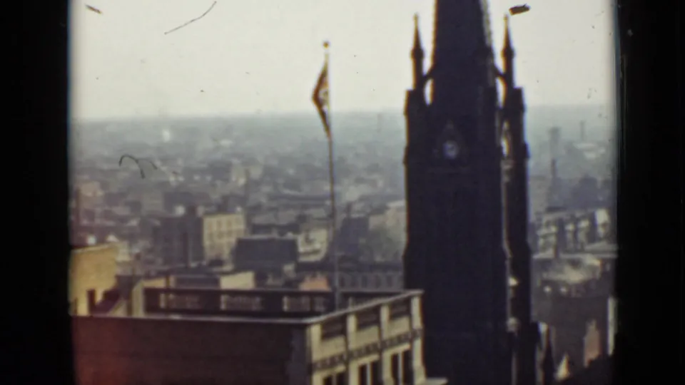 Final 1940 Ontario frame showing the clock tower near the right edge with a flagpole and city buildings beyond.