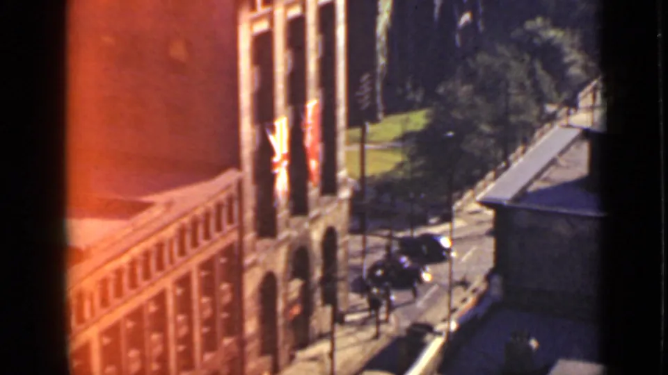 High-angle Ontario street scene with a flagged brick building, trees, sidewalks, and dark 1940s-era automobiles.