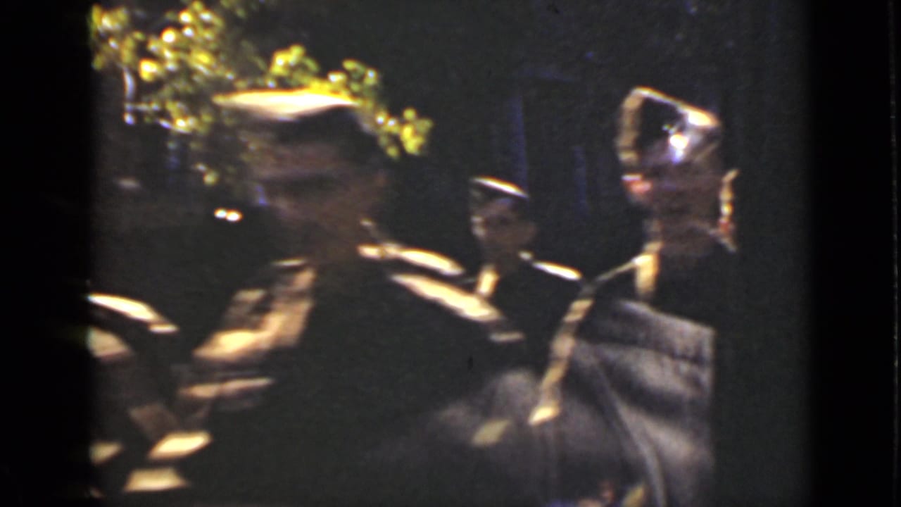 1940 Ontario home-movie frame showing uniformed soldiers in peaked caps passing near a reflective bus or street window.