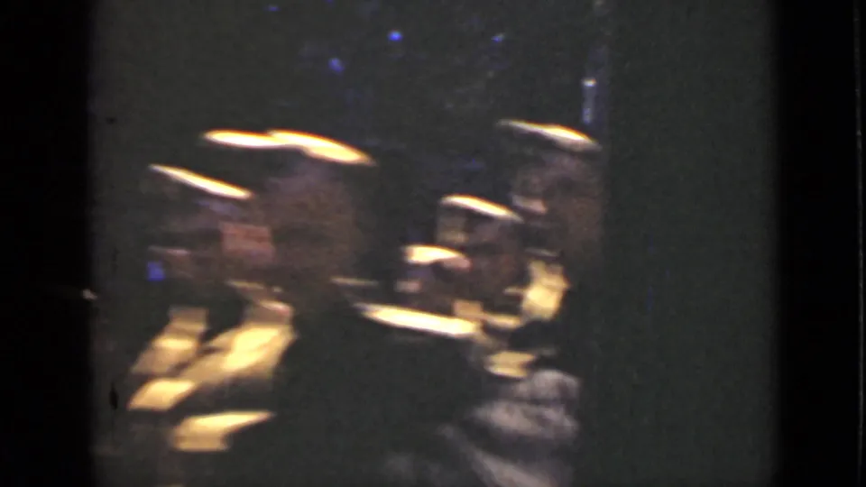 Uniformed men appear in motion near a window reflection in this 1940 Ontario street-march frame.