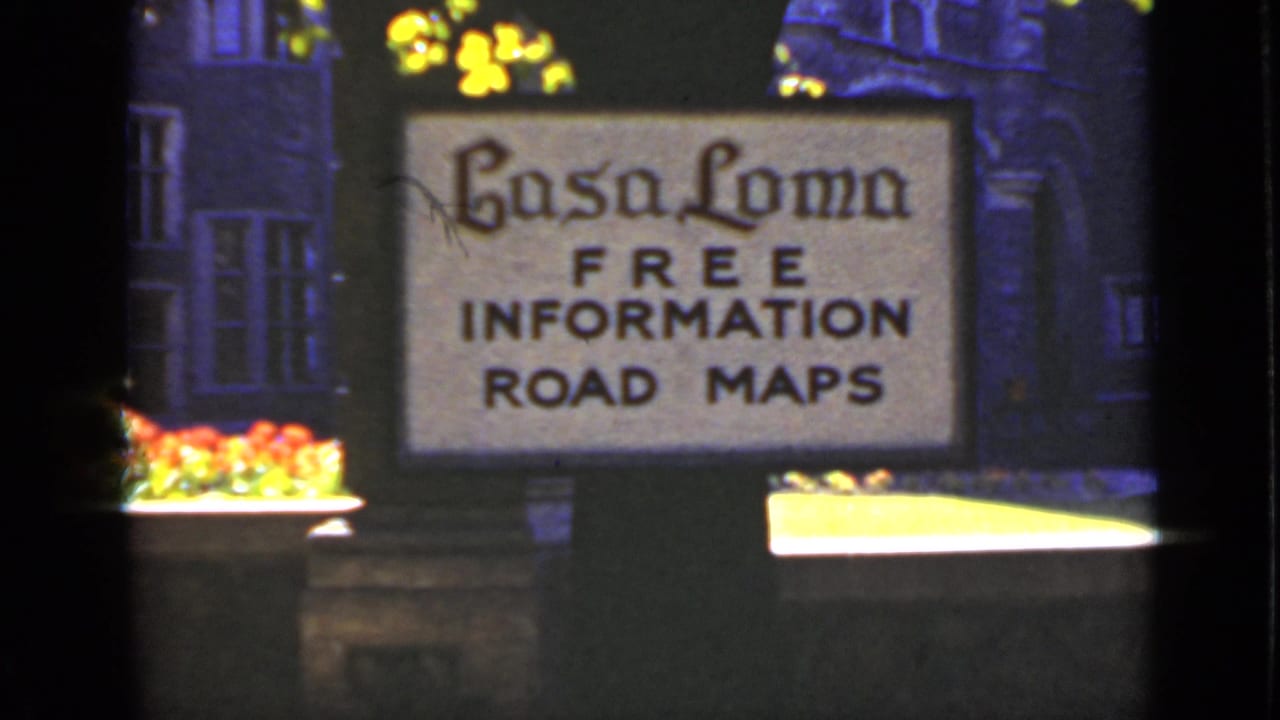 Casa Loma sign advertising free information and road maps beside flowers.