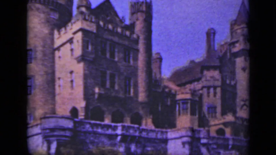 1940 Ontario 8mm frame showing Casa Loma's stone exterior with towers, turrets, arched openings, windows, and a terrace wall.