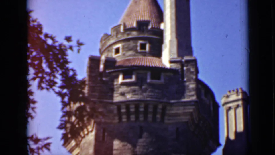 1940 Ontario 8mm frame of the castle-like stone building focused on a round turret, tall chimney, and small windows.