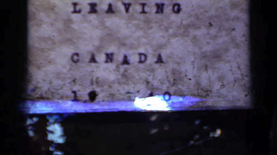 The departure title card remains visible but is partly obscured by flare or projection light along the lower edge.
