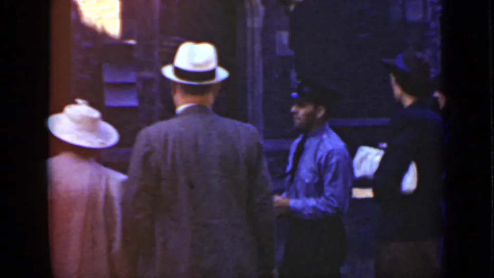 1940 Ontario waterfront frame showing formally dressed adults and a uniformed worker beside the dock.