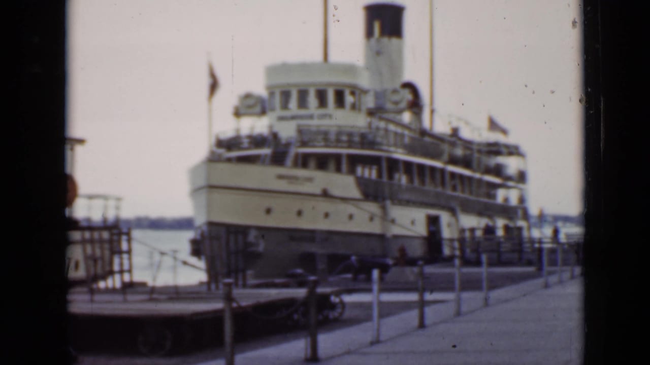 Large steamship moored beside a dock with railings and water behind it.