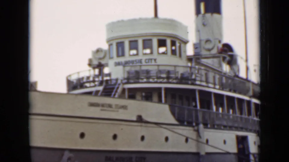 1940 Ontario home-movie frame showing the Dalhousie City name on a white steamship wheelhouse and the cream hull below.