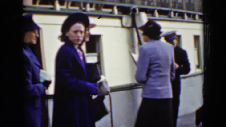 At an Ontario dock in 1940, women in blue and purple coats and hats stand beside the Dalhousie City during boarding.