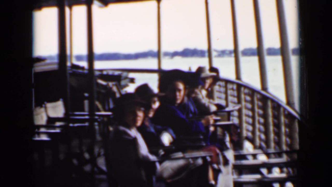 Passengers sit on benches along a ship deck with open water beyond.