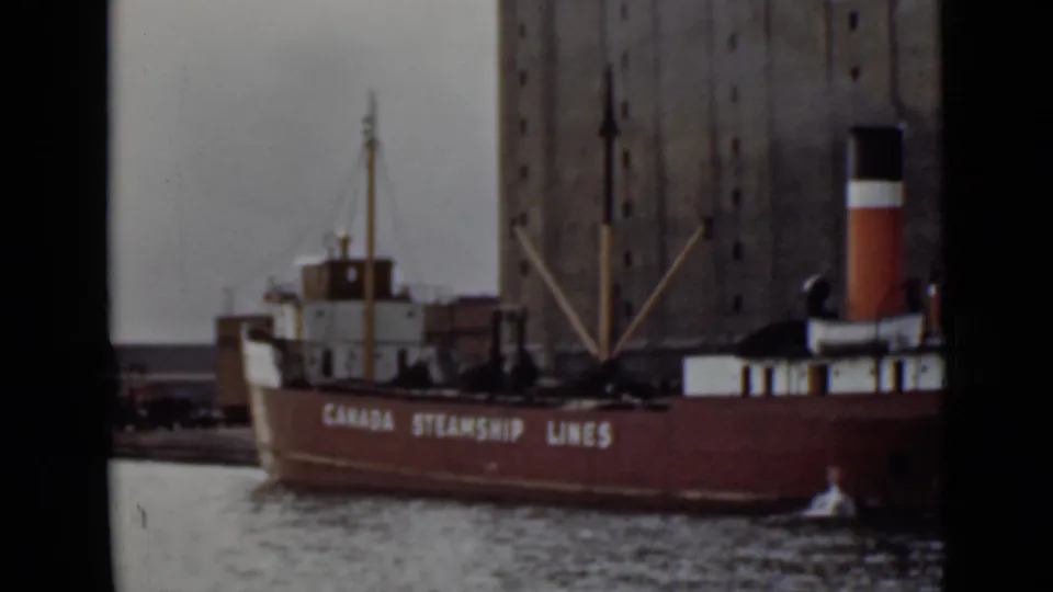 1940s Ontario harbor view of a red Canada Steamship Lines vessel moored near a tall grain elevator.