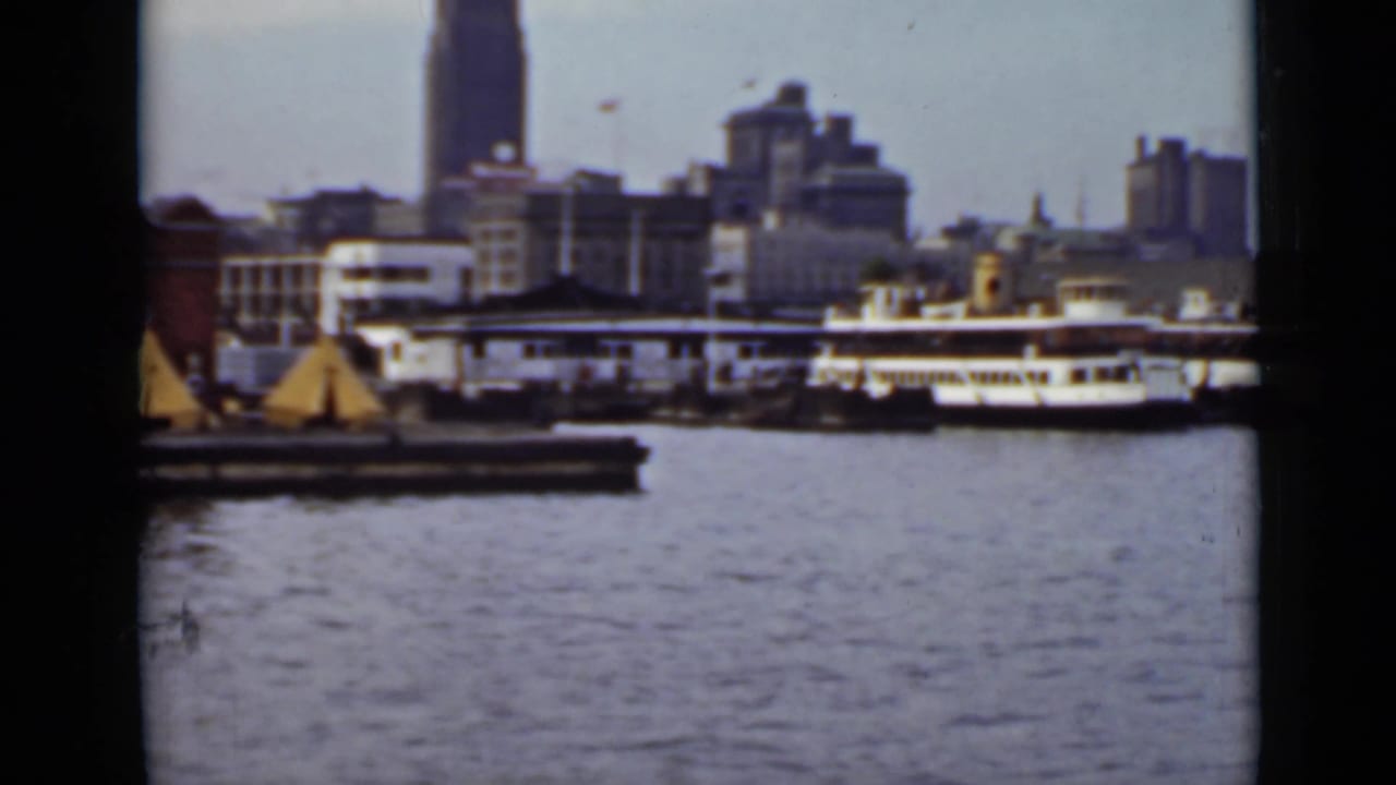 Harbor water with docked passenger boats and a city skyline beyond.