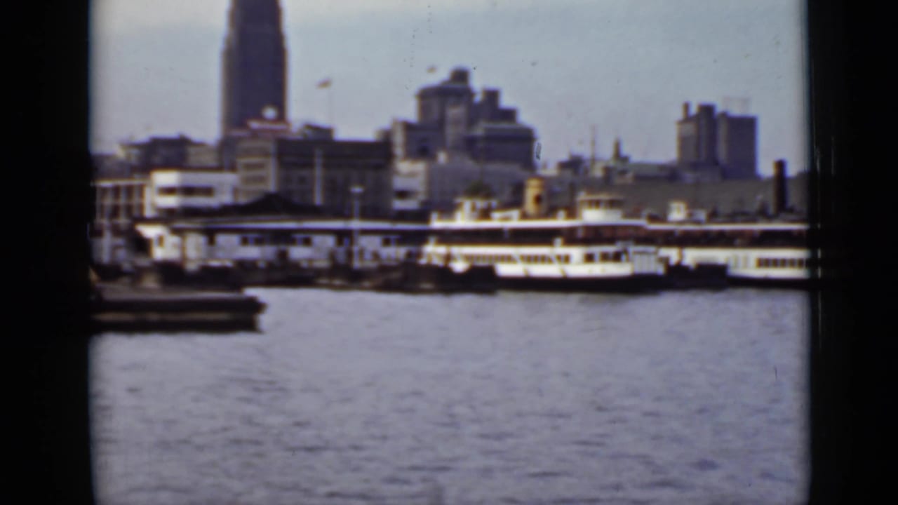 Passenger boats along a waterfront with buildings and water in front.