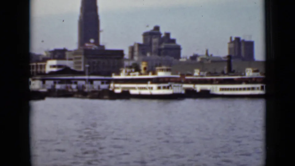 1940 Ontario home-movie view of passenger boats at a city waterfront, with calm water and skyline buildings behind them.
