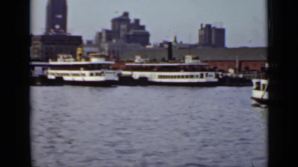 Ontario waterfront scene showing multiple passenger ferries across the water with mid-century urban buildings beyond.