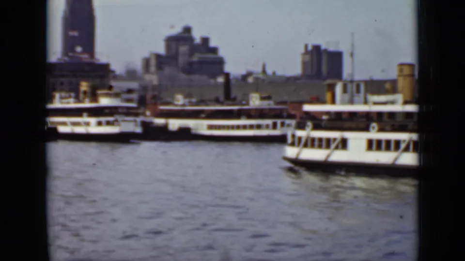 A large white passenger ferry passes closer to camera on an Ontario waterfront, with other ferries and city buildings behind.