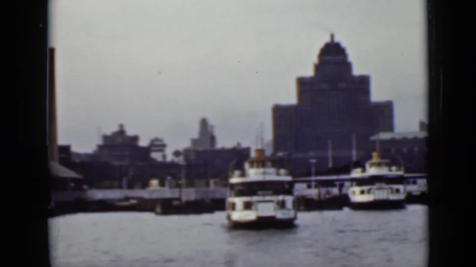 Ontario harbor scene from 1940s home-movie footage, showing ferries near docks and a domed tower in the background.