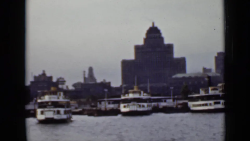 1940 Ontario waterfront view from the water, showing docked passenger boats and a large towered building in the background.
