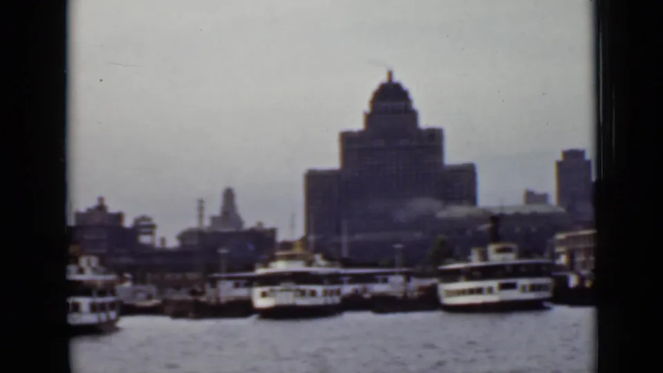 1940 Ontario harbor view with passenger boats, smaller craft, dock structures, and a prominent building rising behind the marina.